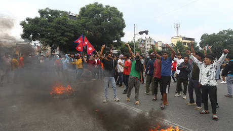 People stand near burning barricades during protests in Kathmandu, Nepal, 09 September 2025.