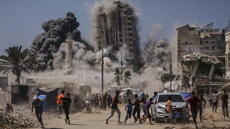 Palestinians run for cover during an Israeli airstrike on a high-rise building in Gaza City, September 5, 2025.