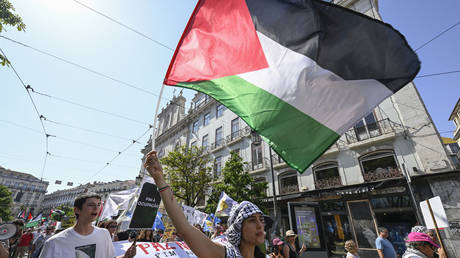Participants parade with Palestinian flags and protest signs during demonstration in Lisbon, Portugal, July, 2025.