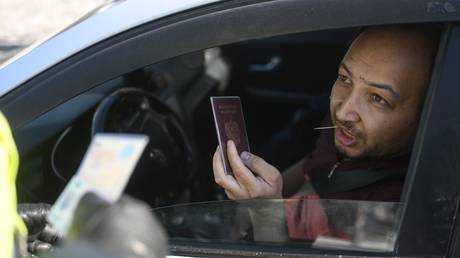 A traffic police officer checks documents of a taxi driver during a raid to identify illegal migrants.