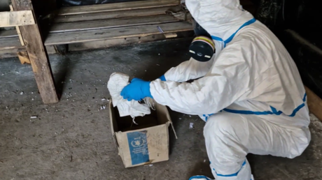 Russian experts in hazmat suits inspect an abandoned Ukrainian makeshift lab.