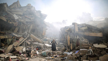 FILE PHOTO. A resident gets upset as she walks amid near the rubble of residential buildings after Israeli airstrikes at al-Zahra neighborhood in Gaza Strip.