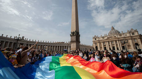 People wave a rainbow flag as Pope Francis addresses the crowd during the Angelus prayer in St. Peter's Square, March 27, 2022.