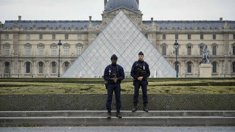 Police stand guard outside the Louvre on October 19, 2025 in Paris.