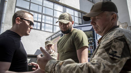 FILE PHOTO: Ukrainian draft officers checking a man’s papers.
